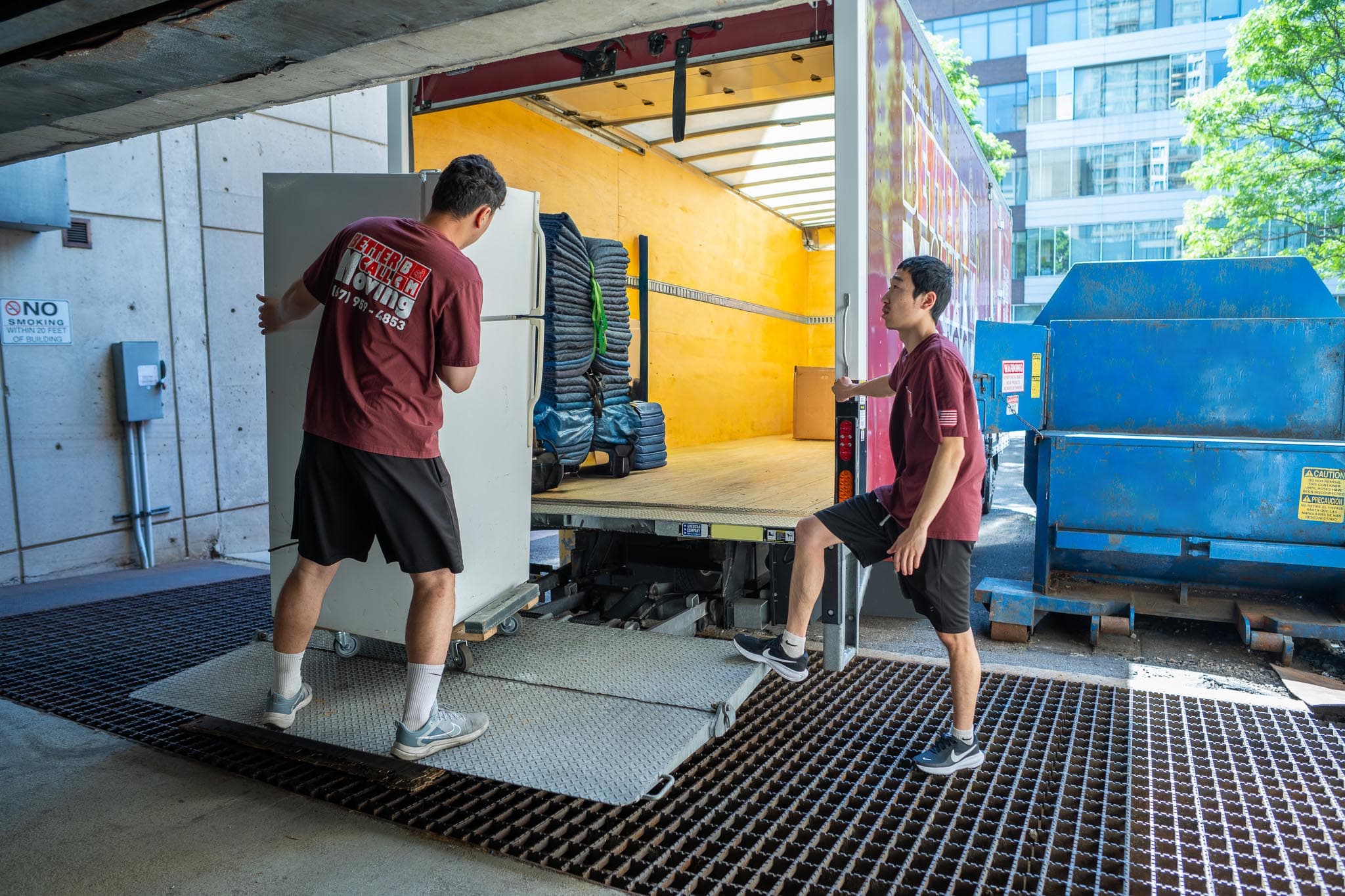 Better Call Moving crew loading a refrigerator onto a truck at a building loading dock
