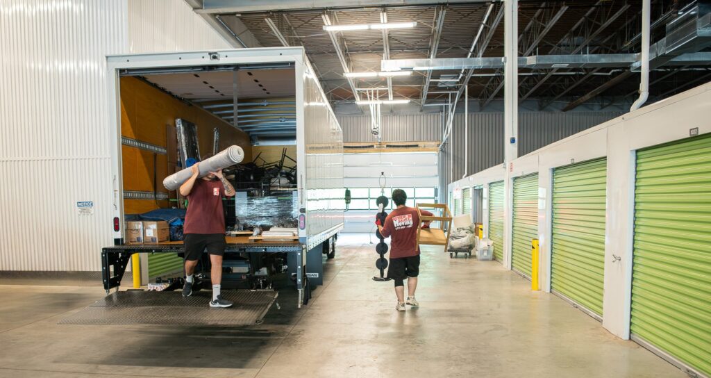 Better Call Moving crew unloading furniture from a truck inside a secure indoor storage facility