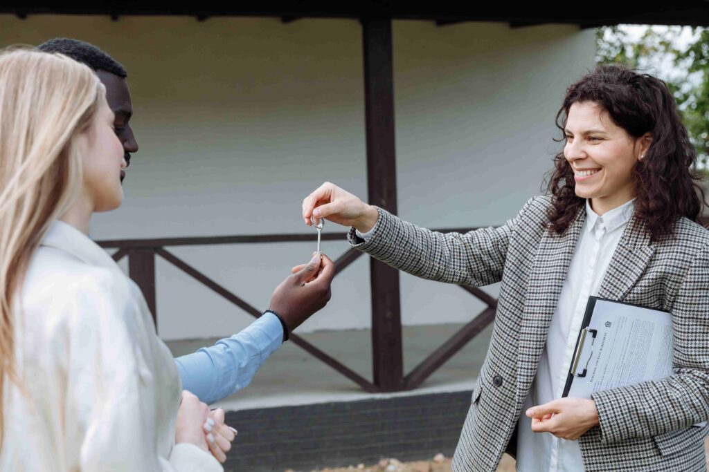 Real estate agent handing house keys to clients after signing the purchase and sale agreement